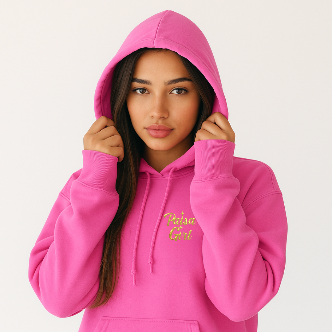 Young Latina model wearing paisa girl sweater hoodie outdoors against neutral wall, azalea pink