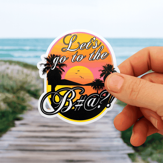 lets go to the bitch sticker held in hand with beach sunset background.