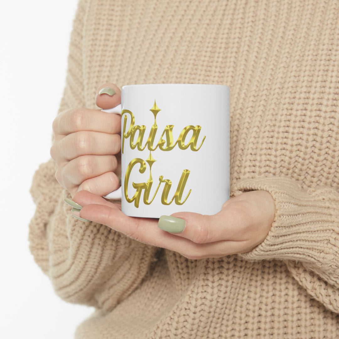 Lifestyle photo of Paisa Girl Ceramic mug with gold lettering in cozy indoor setting.