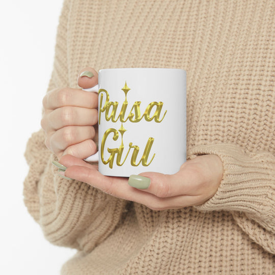 Lifestyle photo of Paisa Girl Ceramic mug with gold lettering in cozy indoor setting.